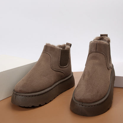 Brown suede ankle boots with fur lining and thick rubber soles on brown and white surface