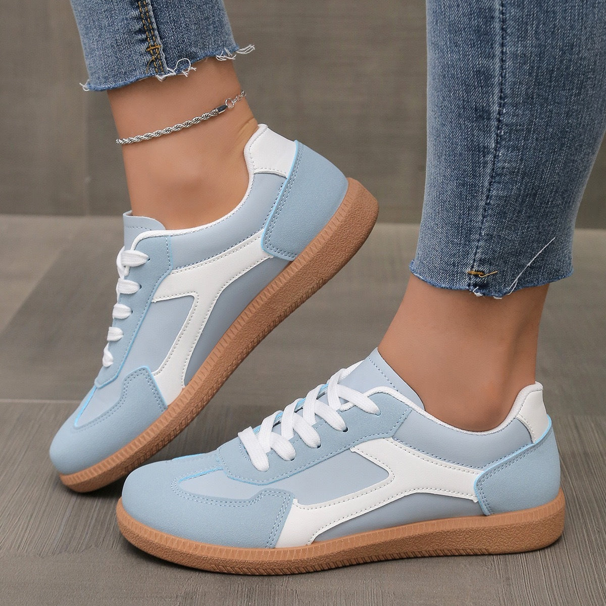 Woman wearing light blue and white casual sneakers with gum soles and cropped denim jeans