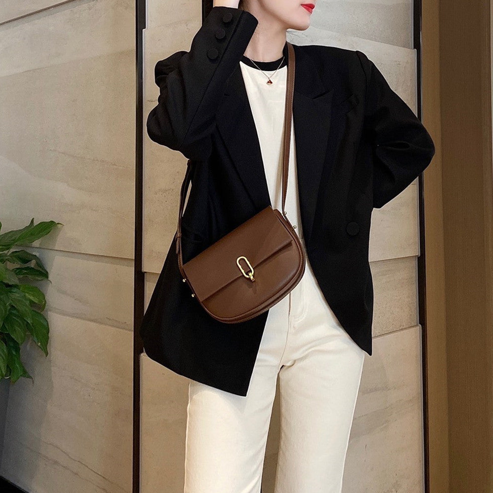 Woman wearing black blazer and white pants with brown leather crossbody bag and red lipstick