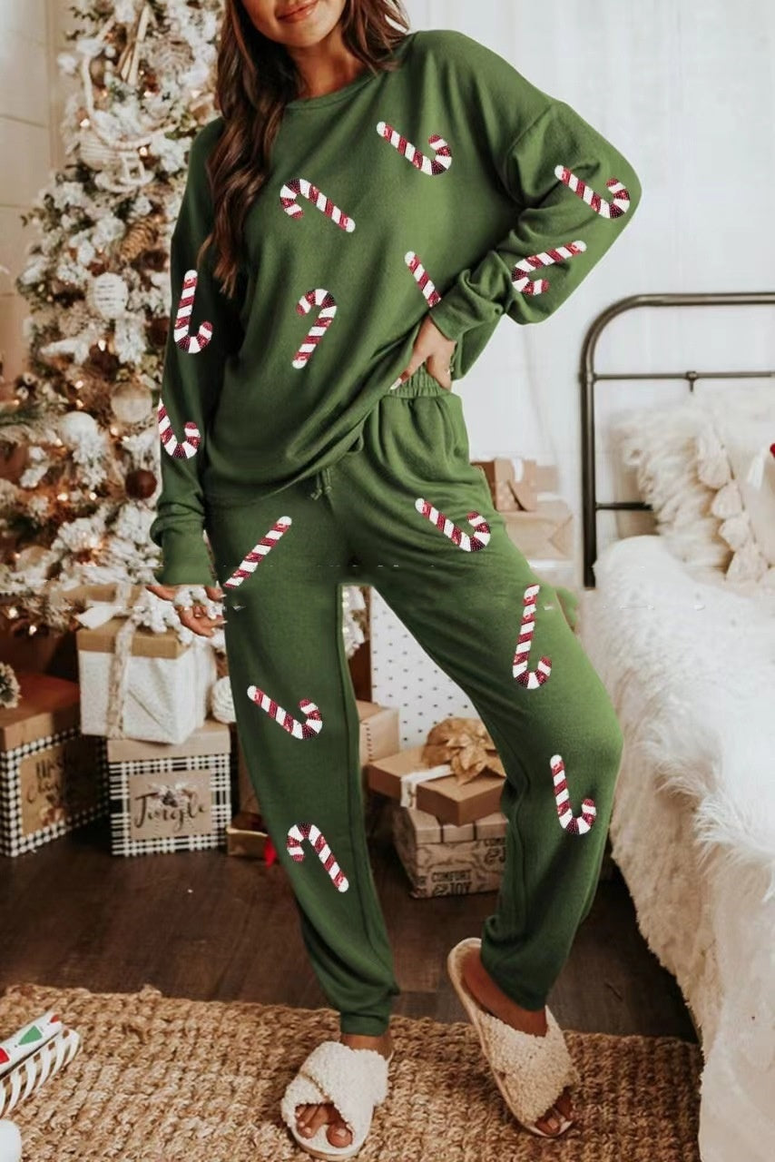 Person wearing a green Christmas-themed outfit with candy cane patterns in a festive room.