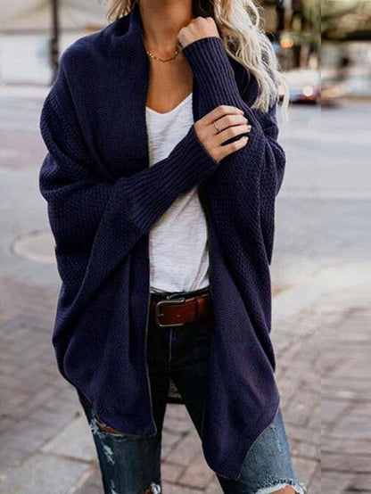 Woman wearing navy blue oversized knit cardigan with white t-shirt and ripped jeans outdoors