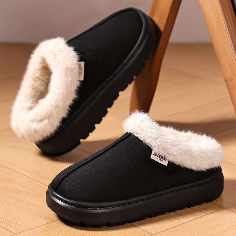 Black slippers with white fur lining on a wooden floor.
