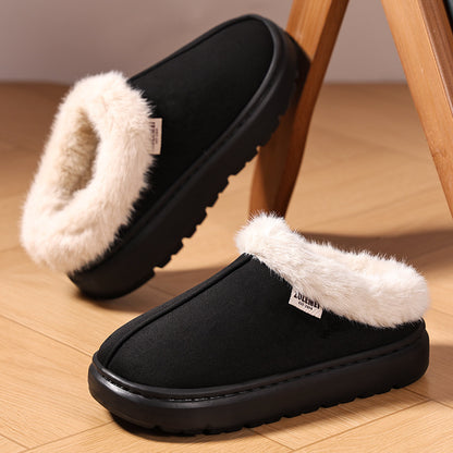 Black slippers with white fur lining on a wooden floor.