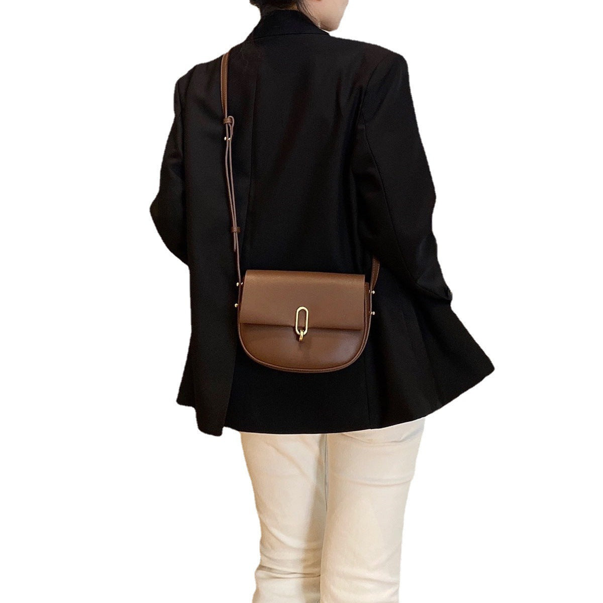 Woman wearing black blazer and white pants with brown leather crossbody bag with gold clasp