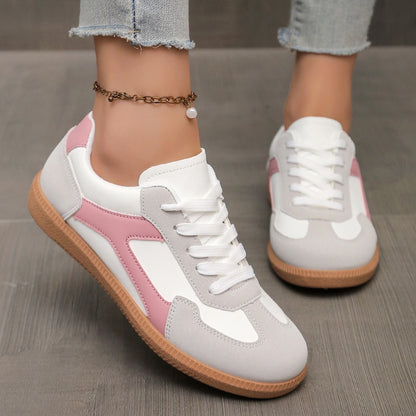 Close-up of white and pink casual sneakers with gum soles worn with ripped blue jeans and an ankle chain