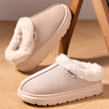 Pair of beige slippers with white fur trim on a wooden floor.
