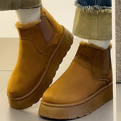 Brown suede winter boots with fur lining worn with white socks and rolled-up jeans on tile floor