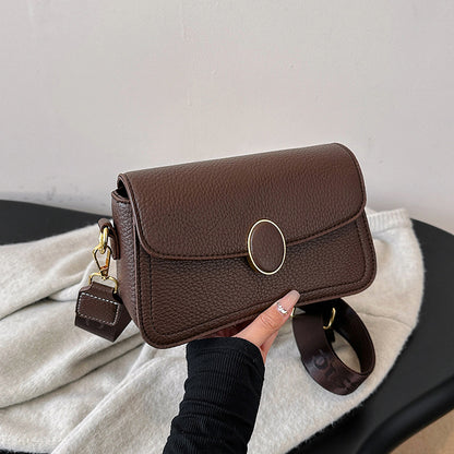 Dark brown textured leather crossbody bag with gold oval clasp and adjustable strap