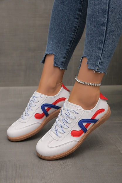 White casual sneakers with blue and red accents on feet wearing frayed hem jeans and a rhinestone anklet