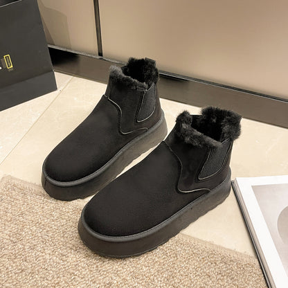 Pair of black suede winter boots with fur lining and thick sole placed on beige tile floor near carpet