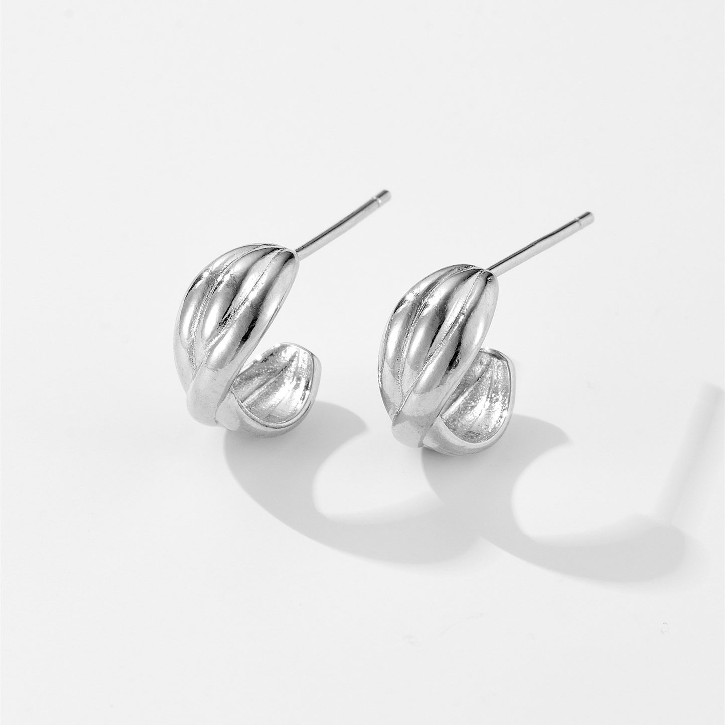 Pair of polished silver twisted hoop stud earrings on white background