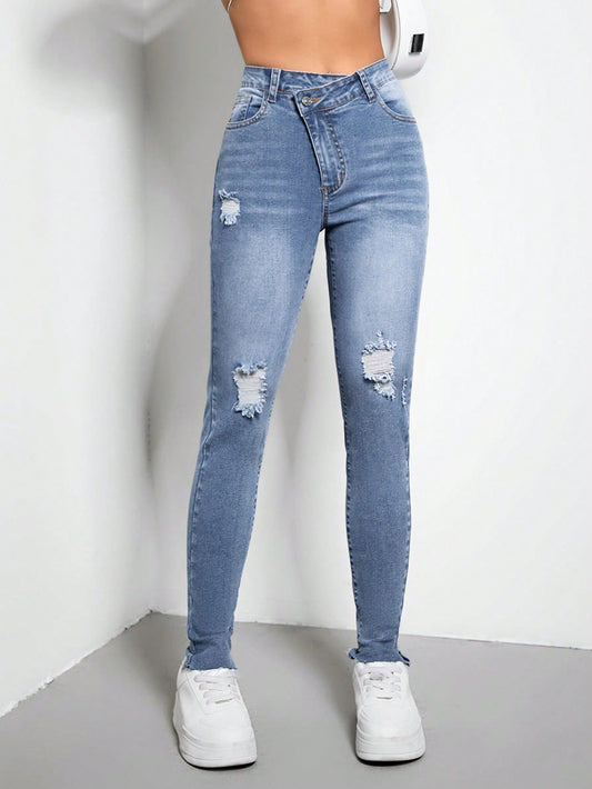 Blue distressed jeans worn by a person on a plain background