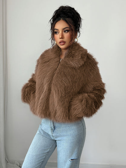 Woman wearing brown faux fur jacket with collar and light blue ripped jeans against white background