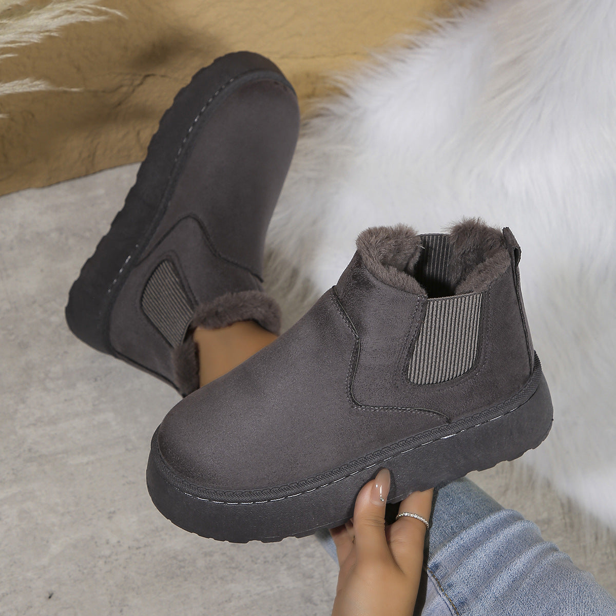 Dark grey suede winter ankle boots with fur lining and elastic side panels worn with jeans