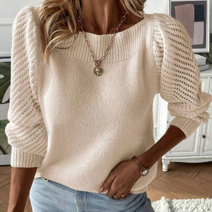 Woman wearing cream knit sweater with puffed openwork sleeves, blue jeans, and gold pendant necklace