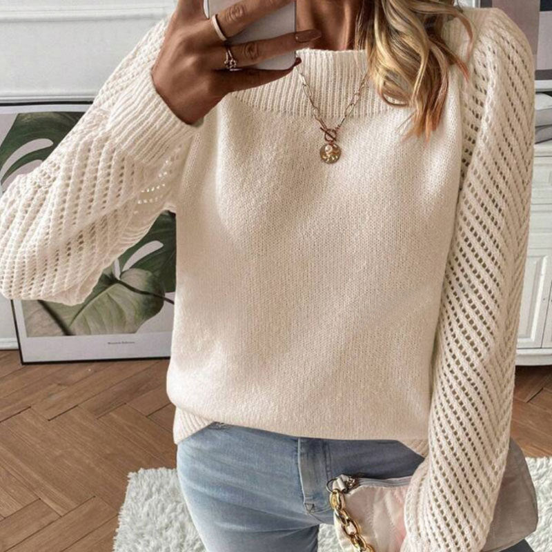 Woman wearing white knit sweater with lace sleeves, blue jeans, and gold pendant necklace