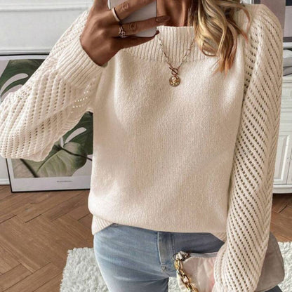Woman wearing white knit sweater with lace sleeves, blue jeans, and gold pendant necklace