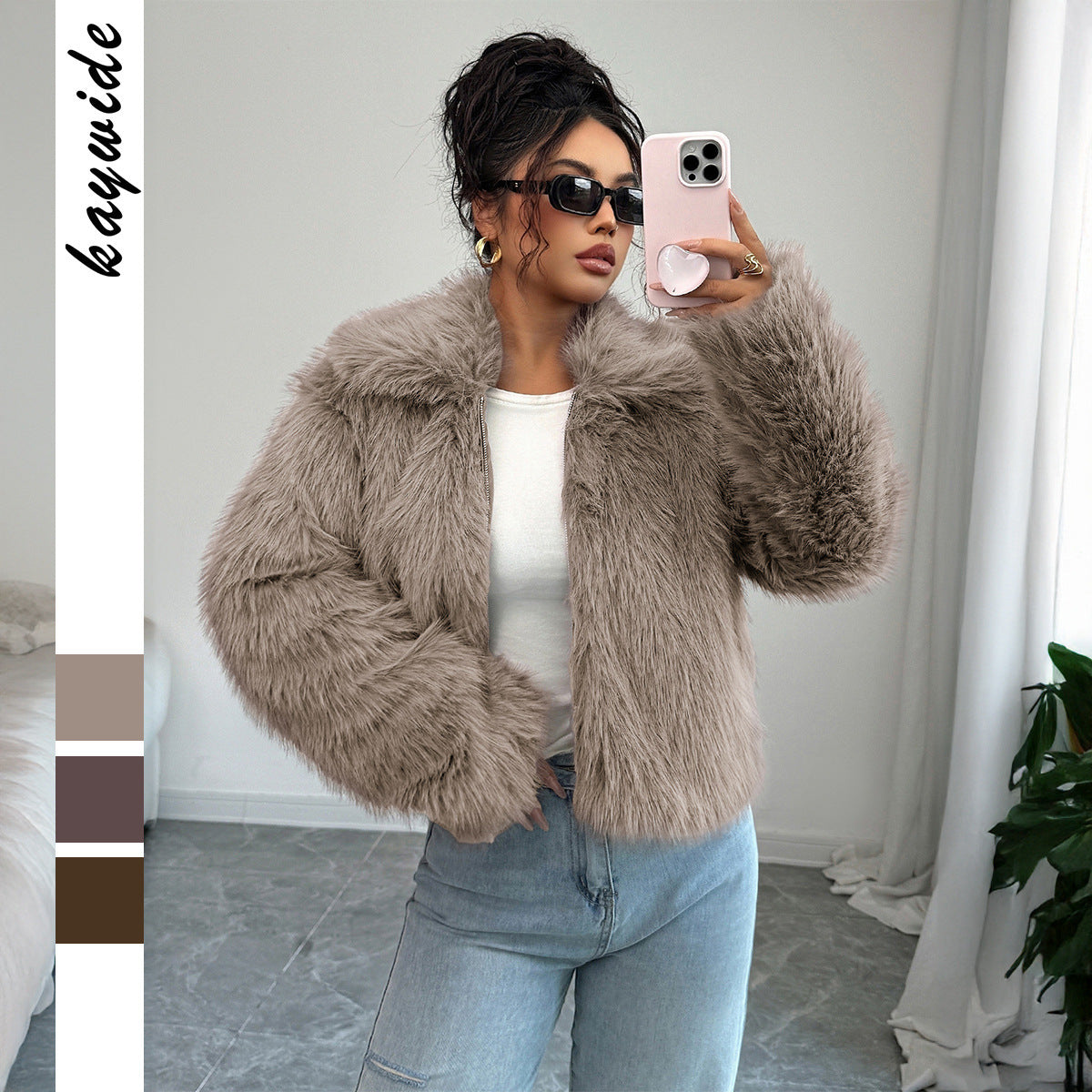 Woman in sunglasses wearing beige faux fur jacket and light blue jeans taking a mirror selfie