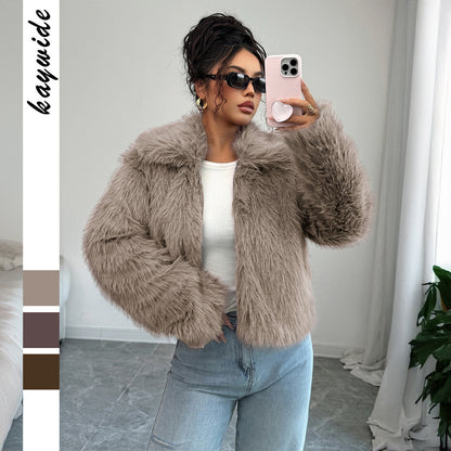 Woman in sunglasses wearing beige faux fur jacket and light blue jeans taking a mirror selfie