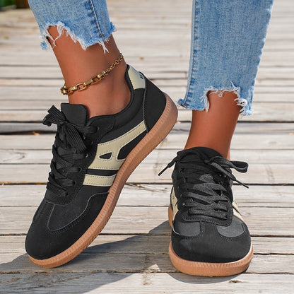 Black and beige sneakers with brown soles on a wooden floor