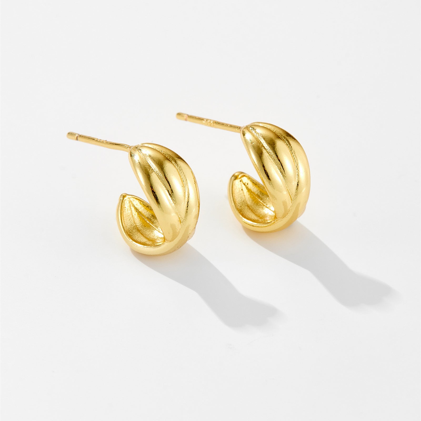 Pair of shiny gold hoop earrings with a twisted design on white background