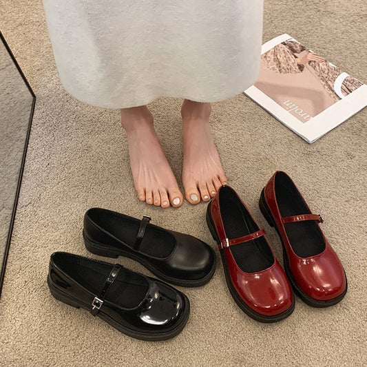 Black and red shoes on a beige carpet with a magazine in the background