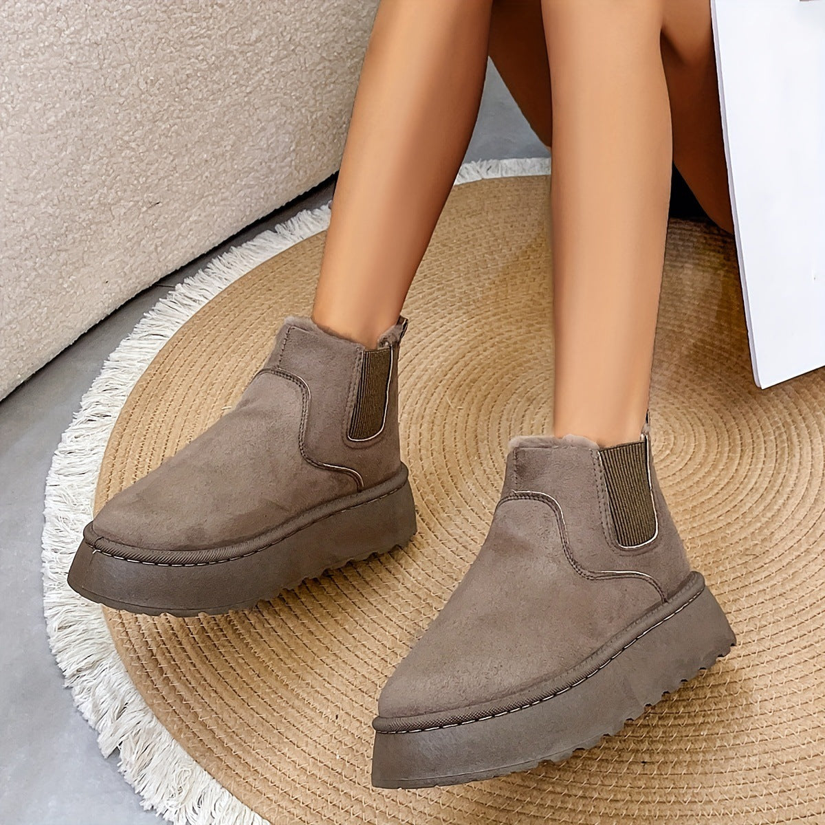 Women wearing taupe suede platform ankle boots with elastic side panels, sitting on round beige rug