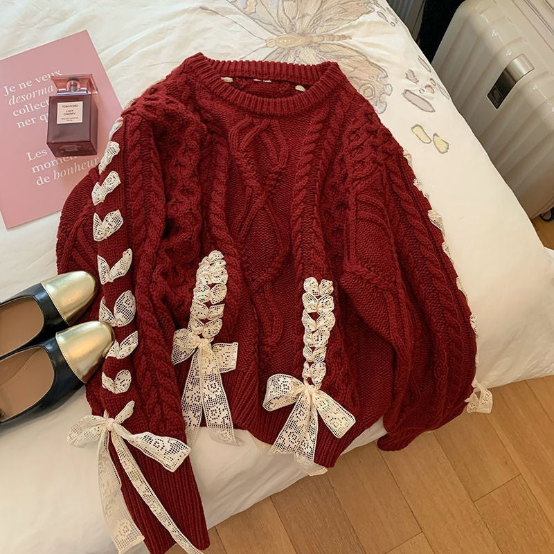 Red cable knit sweater with decorative bows on a bed
