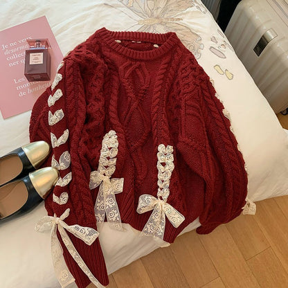 Red cable knit sweater with decorative bows on a bed