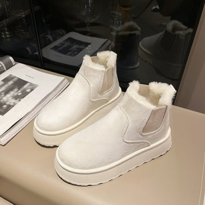 Pair of white winter ankle boots with faux fur lining on beige surface next to an open magazine