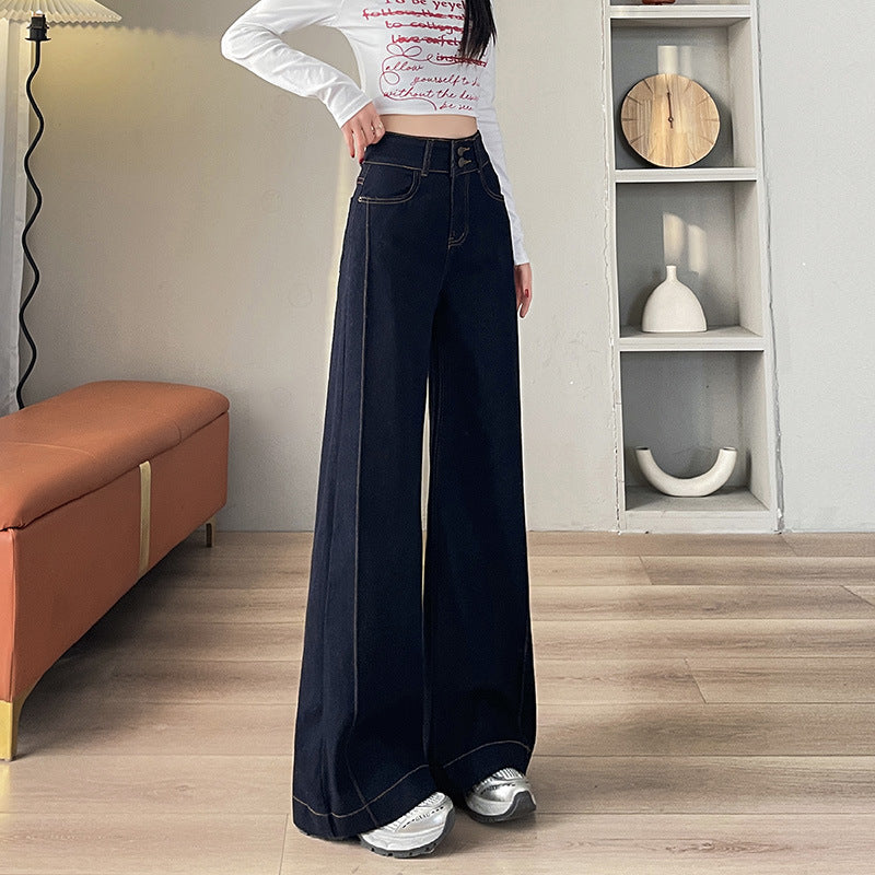 Woman wearing high-waist wide leg dark blue jeans and white printed long sleeve crop top indoors