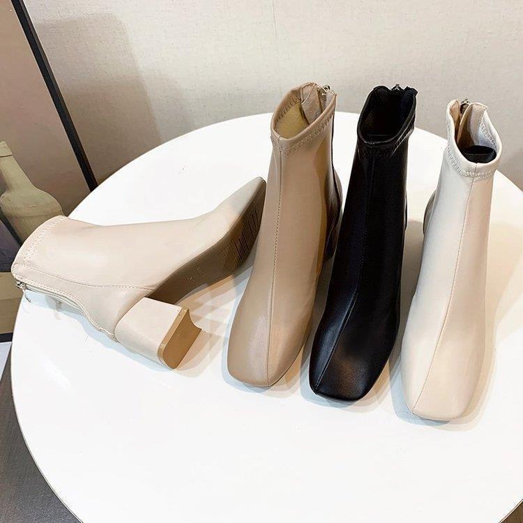 Stylish women's ankle boots in beige, black, and cream leather with block heels on white round table